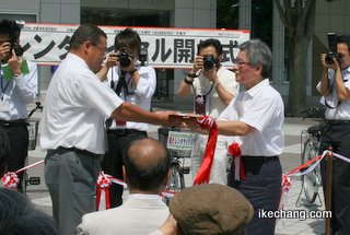 写真:レンタサイクルのカギを受け取る伊藤彰(いとう・あきら)天童温泉協同組合理事長