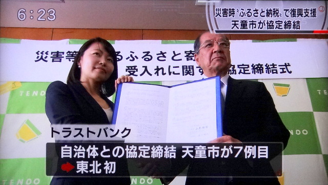 写真：協定書を掲げる山本信治天童市長と須永珠代代表取締役社長