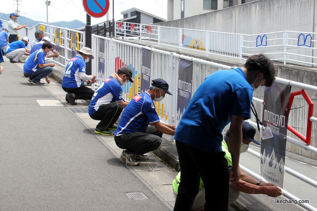 画像：歩道フェンスにタペストリーを取り付ける天童市モンテ応援隊のみなさん