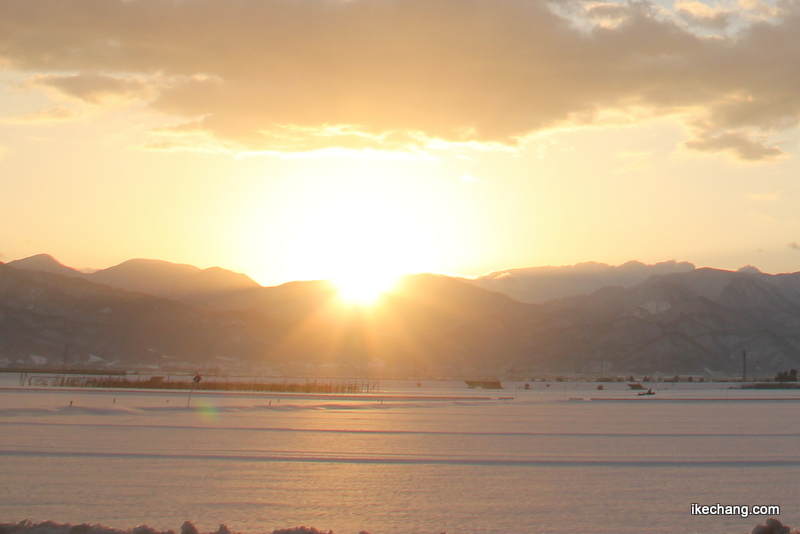 画像：朝日で赤く染まる、雪が積もった田んぼ