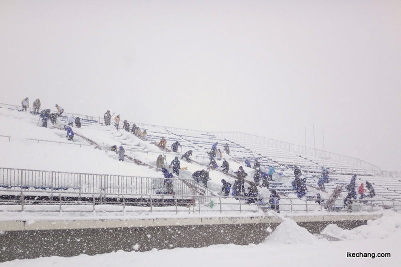 写真：吹雪のなかバックスタンド北側を除雪作業