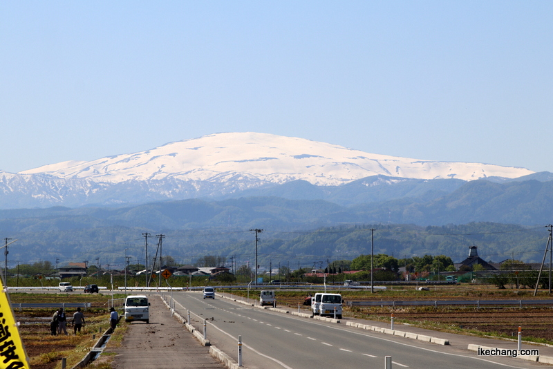 写真：青空に白く輝く月山と農家の皆さん